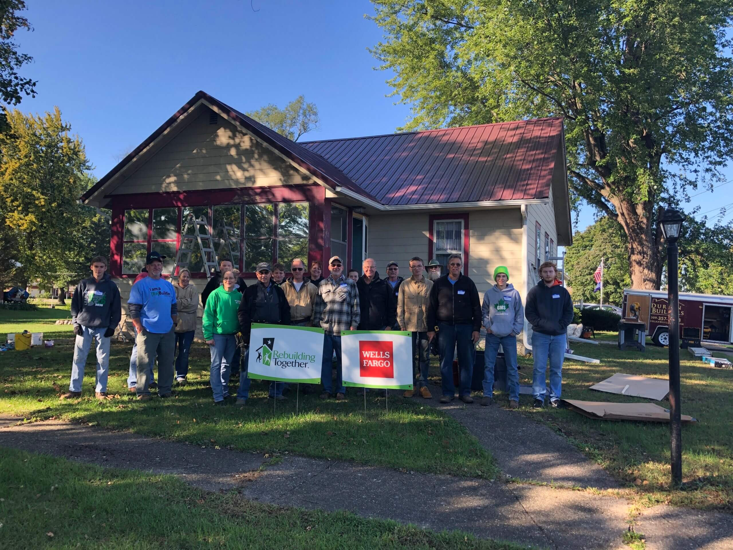 Rebuilding Together workers pose in front of a home
